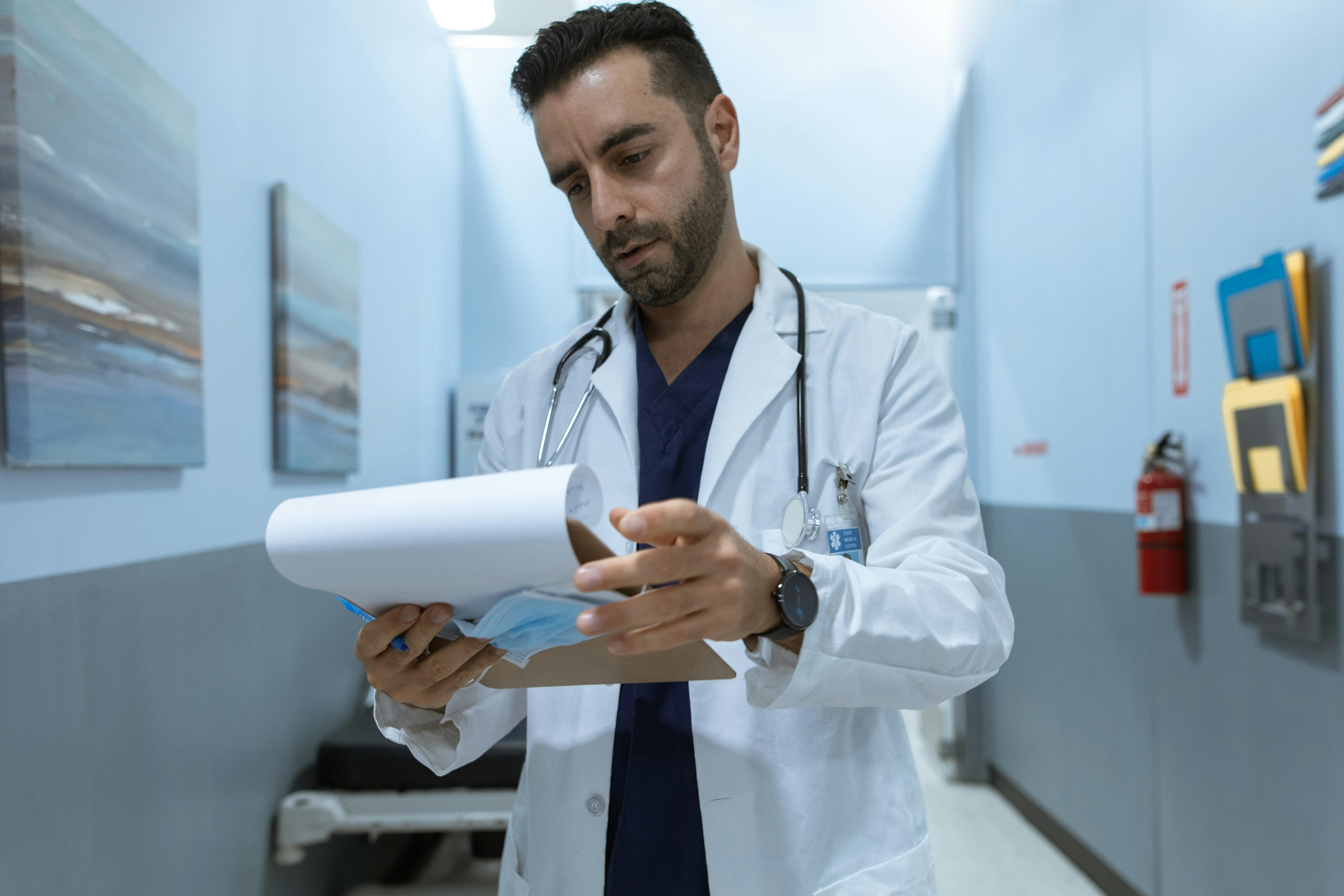 A male physician and perfectionism therapy client reviews test results while alone in a
hospital hallway. He appears stressed and overwhelmed at work.